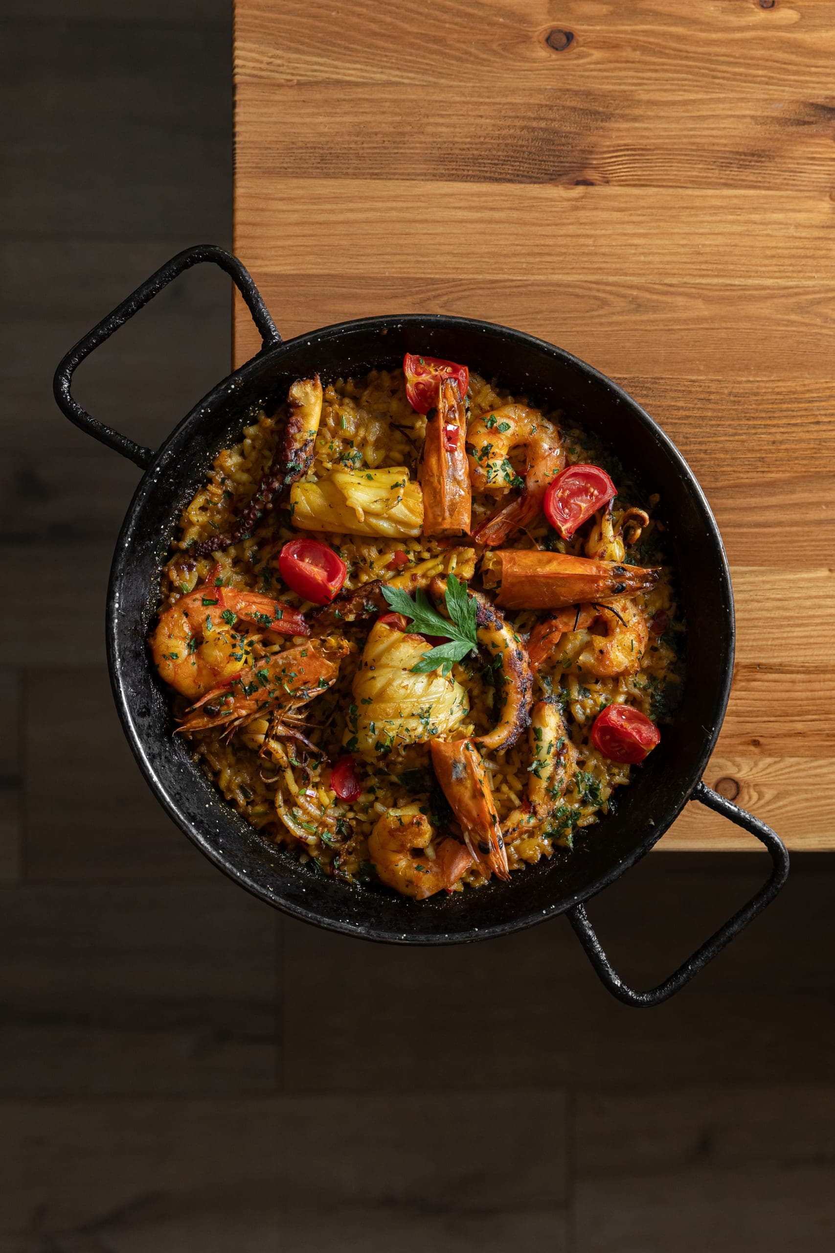 Seafood paella with prawns, squid and peppers in a cast iron pan, seen from above